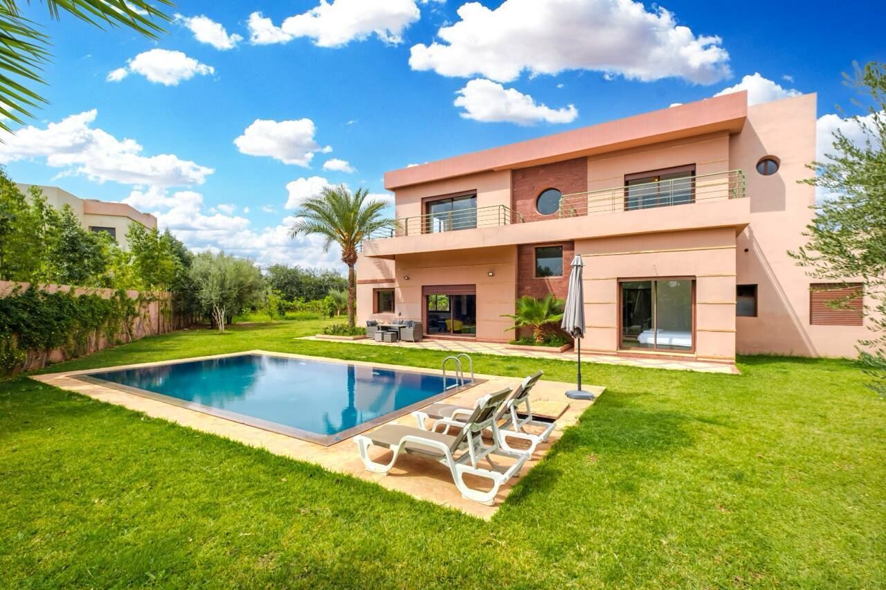 A modern two-story house with a swimming pool, outdoor seating, and a well-maintained garden.