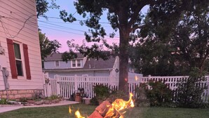 Un hogar con leña ardiendo en una estructura metálica, rodeado por un patio de ladrillo.