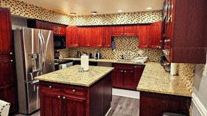 A modern kitchen with dark wooden cabinets, stainless steel appliances, and a patterned backsplash.