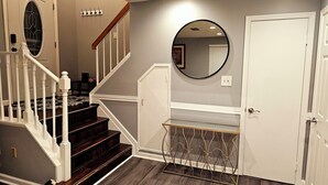 A staircase with white railings and dark wood steps, leading to a landing with a glass partition and a round mirror on the wall.