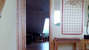 A room with wooden flooring, a bench, a red hanging rack, and a doorway leading to another room. - Ferienwohnung mit Fahrrädern und Garten (Müncheberg)