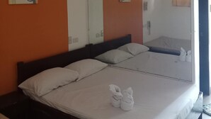 A hotel room with a large bed, two pillows, a mirror, and a painting on the wall. - Moonlight lodge (Puerto Princesa)