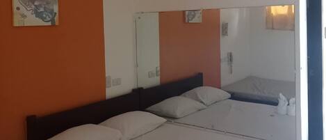 A hotel room with a large bed, two pillows, a mirror, and a painting on the wall.