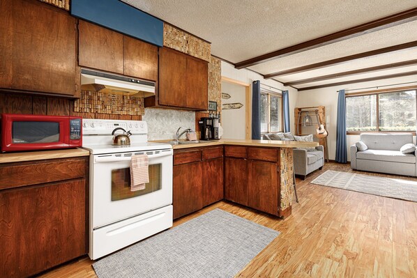 A kitchen with wooden cabinets, a white stove, and a red microwave. - Cinders Whispering Waters and Wilderness Escape (Beulah)