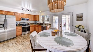 Une cuisine moderne avec des meubles en bois, des appareils en acier inoxydable et un coin repas comprenant une table ronde et des chaises.