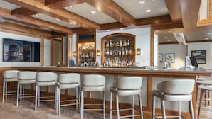 A bar area with wooden beams, a bar counter, and multiple stools. - The Ritz-carlton Club, Vail 4 Bedroom Luxury Residence (Vail)