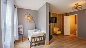 Ein modernes Wohnzimmer mit Holzboden, einem weißen Sofa, einem gelben Sessel und einem an der Wand montierten Fernseher.