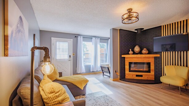 Ein Wohnzimmer mit Kamin, einer Couch, einem gelben Sessel und einer Lampe.