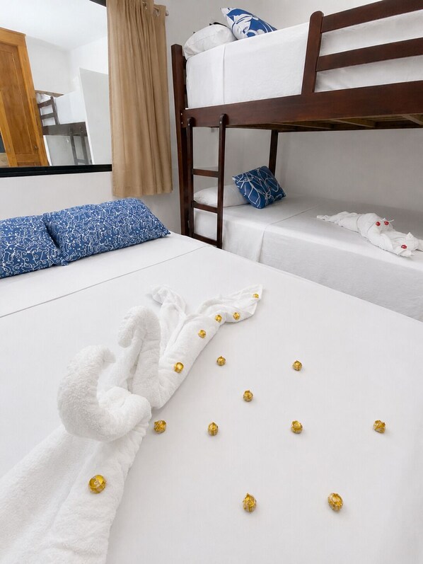 Une chambre d’hôtel avec un lit superposé, une couvre-lit blanche et un peignoir blanc orné de boutons dorés.