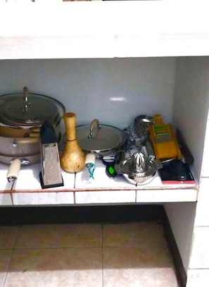 En köksbänk med diverse föremål, inklusive ett rivjärn, en kastrull med lock, en flaska och en juicer.