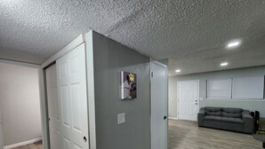 Een ruime woonkamer met een grijze wand, een grijze bank en een houten vloer.