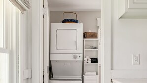 Una cocina compacta con refrigerador incorporado, un taburete de madera y un armario blanco.