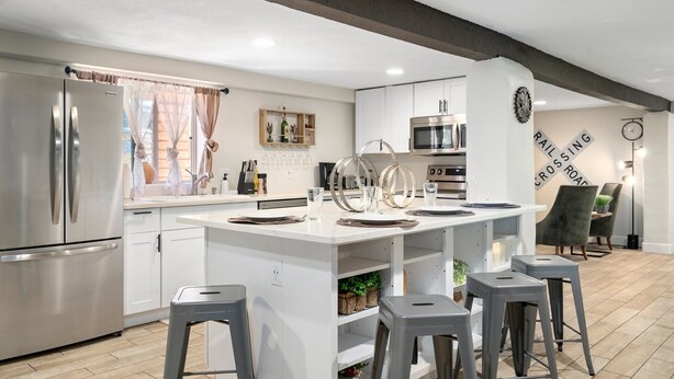 Una cocina moderna con una isla central, electrodomésticos de acero inoxidable y una zona de comedor con taburetes de bar.