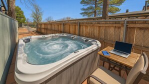 Un jacuzzi con una computadora portátil sobre una mesa de madera a su lado.