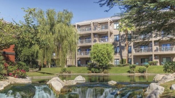 A multi-story hotel with a landscaped garden, a small waterfall, and a pond. - 1-bedroom villa in charming Indio with AC, WiFi, fitness room (Indio)