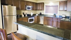 A modern kitchen with granite countertops, stainless steel appliances, and wooden cabinets. - 1-bedroom villa in charming Indio with AC, WiFi, fitness room (Indio)