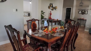 A dining room with a wooden table set for six, surrounded by upholstered chairs.