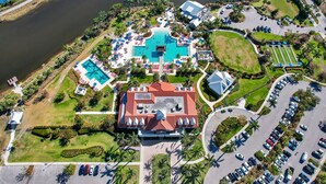 An aerial view of a resort with multiple swimming pools, a large central building, and a parking area. - Saona Cottage - Coastal Elegance (Naples)
