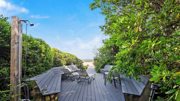 A wooden deck with outdoor seating and a shower.