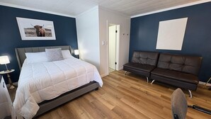 A bedroom with a bed, a sofa, a chair, and a picture on the wall.
