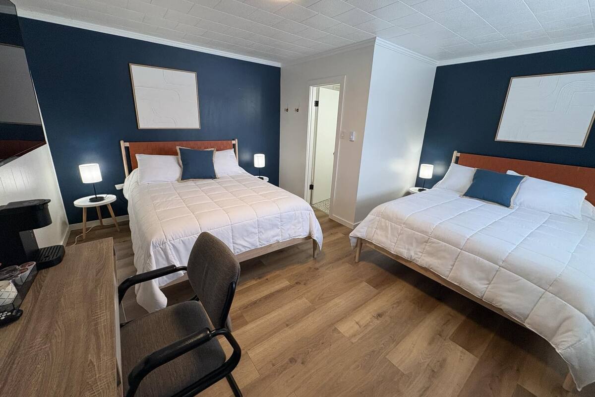 A hotel room with two beds, a desk, and a chair.