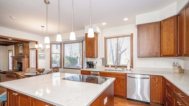 A modern kitchen with wooden cabinets, a large island, and pendant lighting. - Luxurious Dream Home For 10! (Loveland)