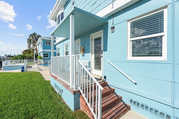 A two-story house with a blue exterior, white trim, and a front porch with steps leading to a door.