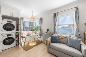 Una cocina moderna con electrodomésticos integrados, un comedor con mesa de vidrio y un sofá con vistas a la ciudad.