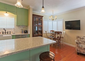 Una cocina con gabinetes verdes, encimera de granito y un comedor con mesa y sillas.