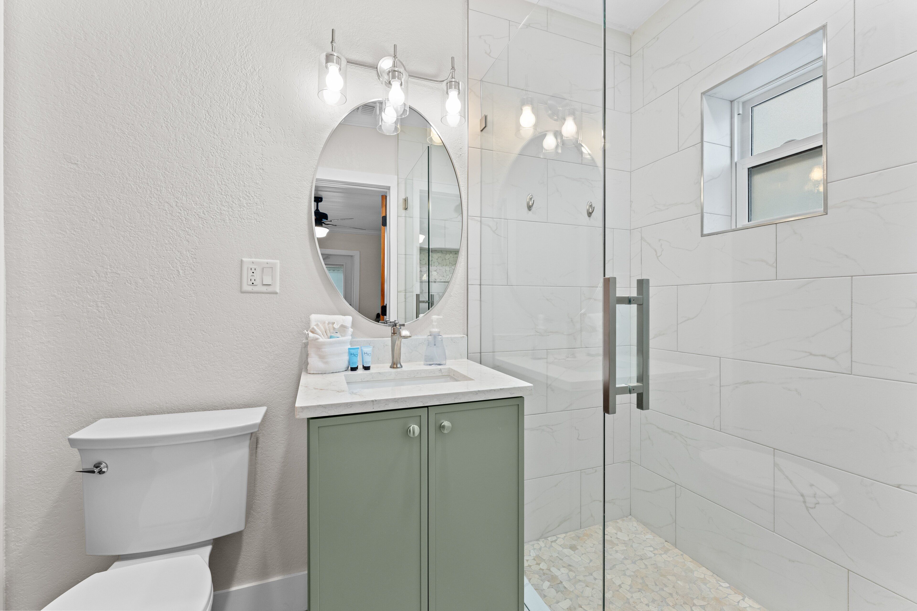 Een badkamer met toilet, wastafel, spiegel en douche.
