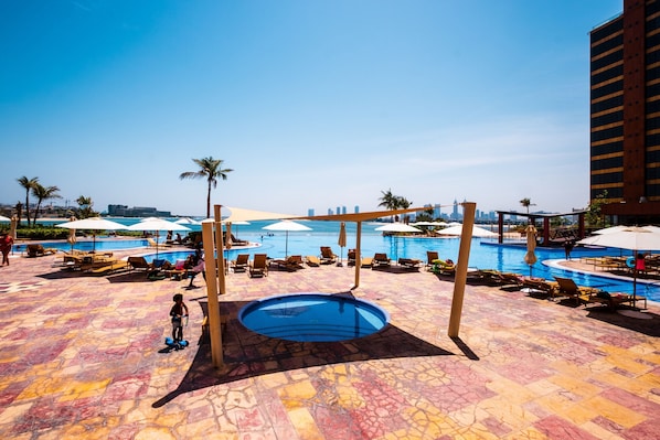 A pool area with lounge chairs and umbrellas, a small pool, and a view of the city skyline.
