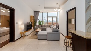 A modern living room with a sectional sofa, a small round table, and a bar area. - 2BR at the Palm | Balcony, Pool, Gym & Beach (Dubai)