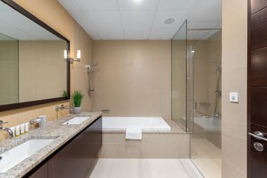 A modern bathroom with two sinks, a bathtub, and a glass-enclosed shower area.
