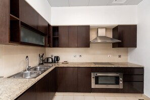 A modern kitchen with dark wood cabinets, a stainless steel sink, and an oven.