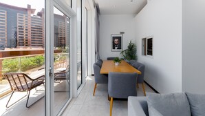 A modern living room with a wooden dining table, grey sofas, and a balcony with wicker chairs. - 2BR at the Palm | Balcony, Pool, Gym & Beach (Dubai)