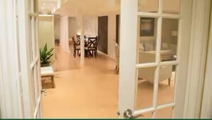 En hotellkorridor med ett matområde och ett sovrum som syns genom en öppen dörr.