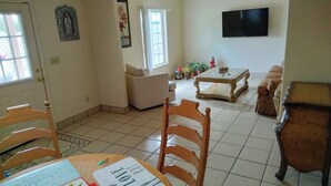 A living room with a sofa, a coffee table, and a TV mounted on the wall.
