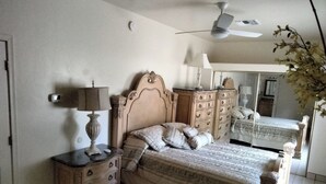 A bedroom with a bed, a dresser, a nightstand, a ceiling fan, and a mirror.