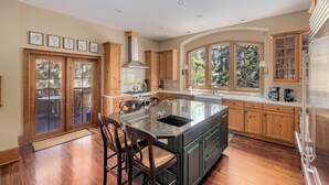 A kitchen with a large island, wooden cabinets, and a view through the glass doors.