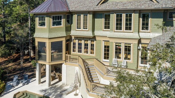 A large, two-story house with a wrap-around porch, a swimming pool, and a covered outdoor seating area.