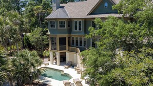 A two-story house with a large front yard, a swimming pool, and a covered patio area.