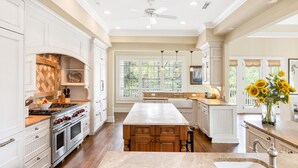 A spacious kitchen with white cabinetry, a central island, and a large window with a view.