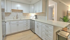 A modern kitchen with white cabinets, a dishwasher, and a countertop with a sink. - Renovated 1BR Condo. Walk to Beach&Salty Dog, Sleeps 5. Bike, Golf, Pickleball! (Hilton Head Island)