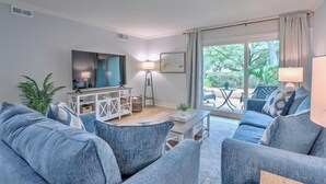 A modern living room with a large flat-screen TV, a coffee table, and a sofa set. - Renovated 1BR Condo. Walk to Beach&Salty Dog, Sleeps 5. Bike, Golf, Pickleball! (Hilton Head Island)