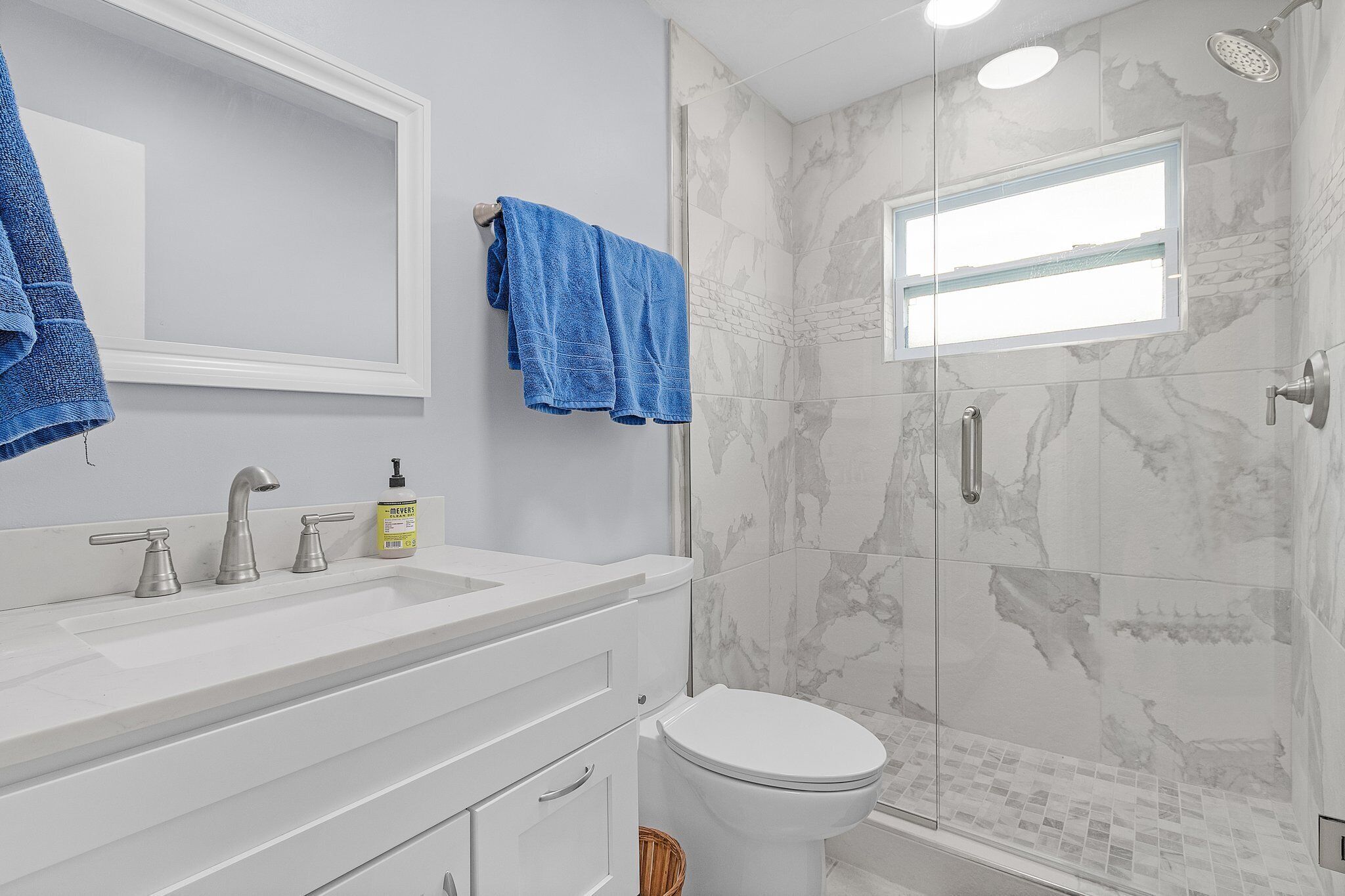 A bathroom with a white sink, three faucets, a toilet, and a shower with a glass door.