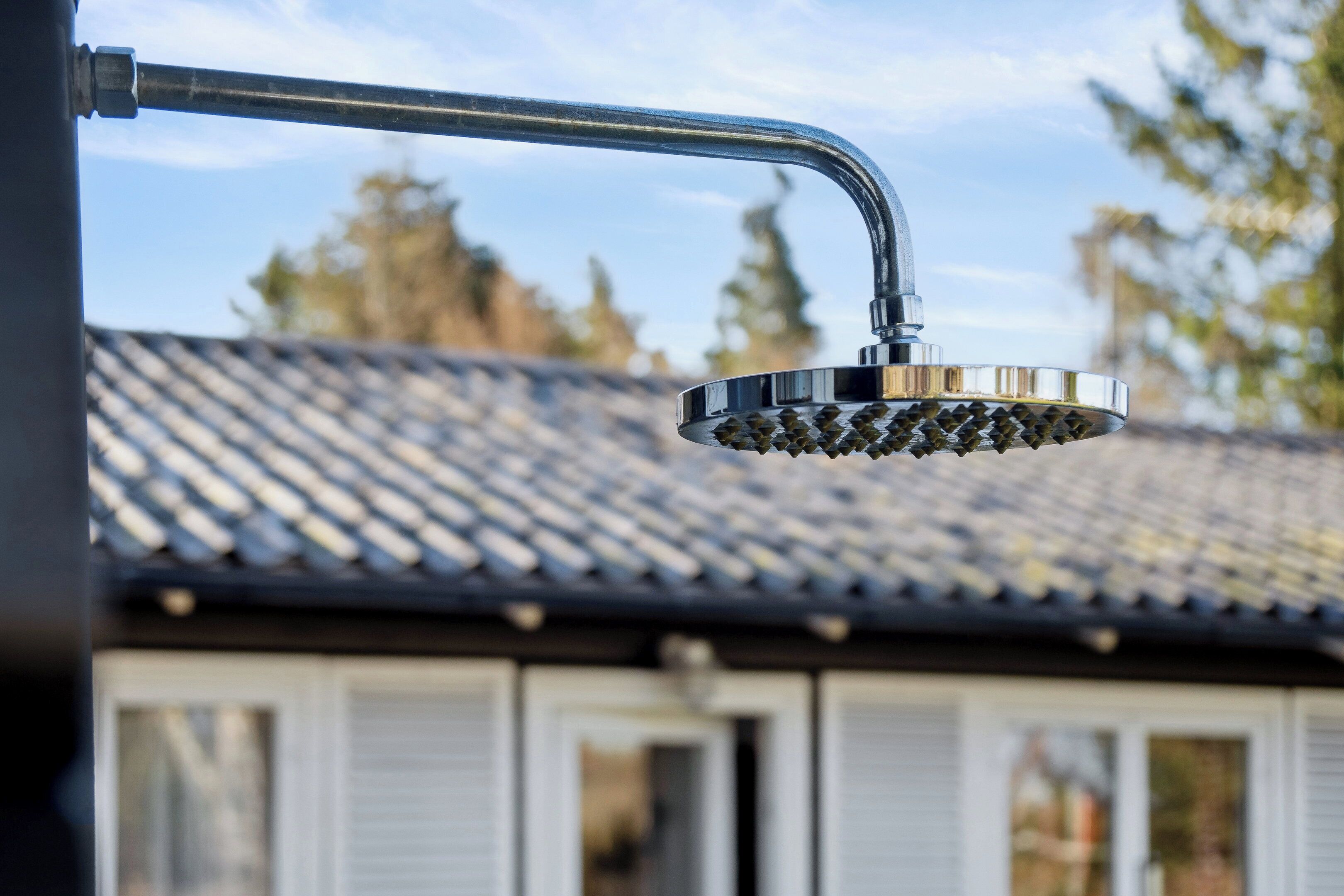 Een douchekop met een gebogen pijp en een ronde voet, bevestigd aan een metalen constructie.