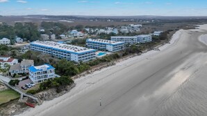 Un hotel frente al mar con varias edificaciones, una playa y cielo despejado.