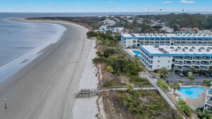 Un hotel frente a la playa con piscina, paseo marítimo y vista al océano.