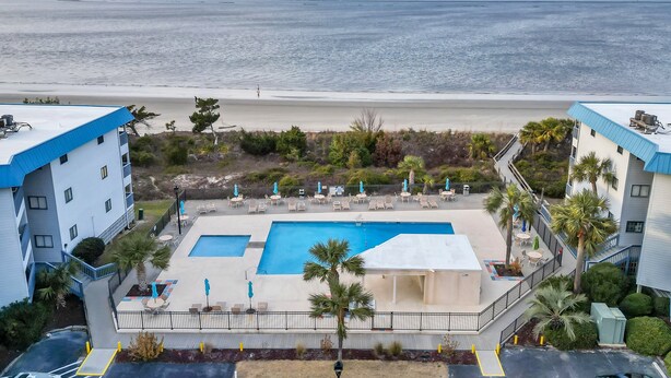 Un hotel con piscina, vistas a la playa y zona de estar al aire libre.