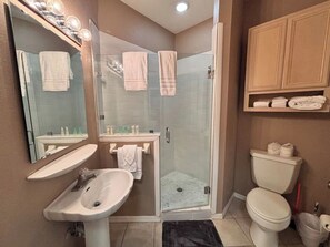A bathroom with a sink, mirror, shower, and toilet.